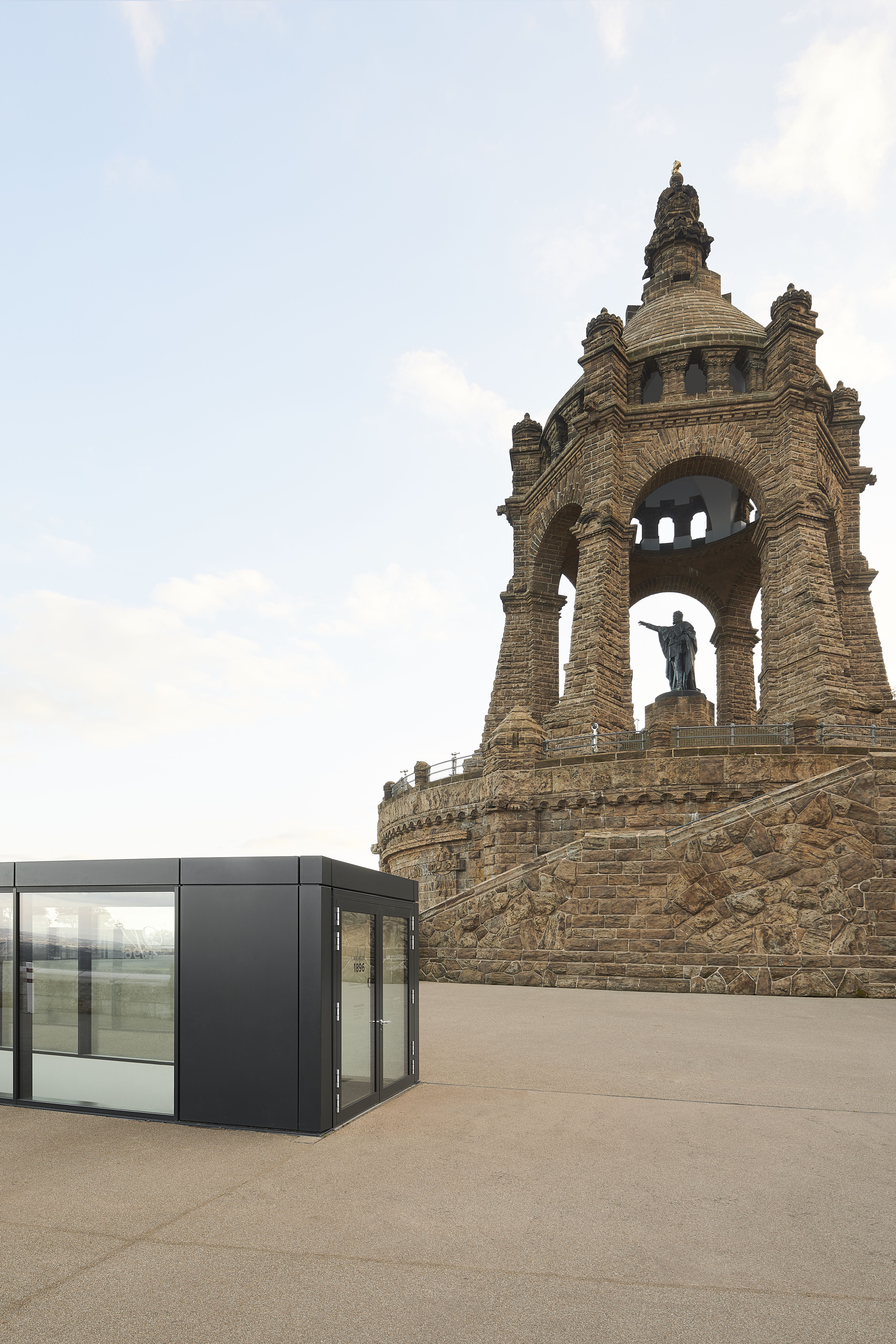 Monumentale Steinskulptur mit großem Torbogen und Reiterstandbild auf einem Podest.