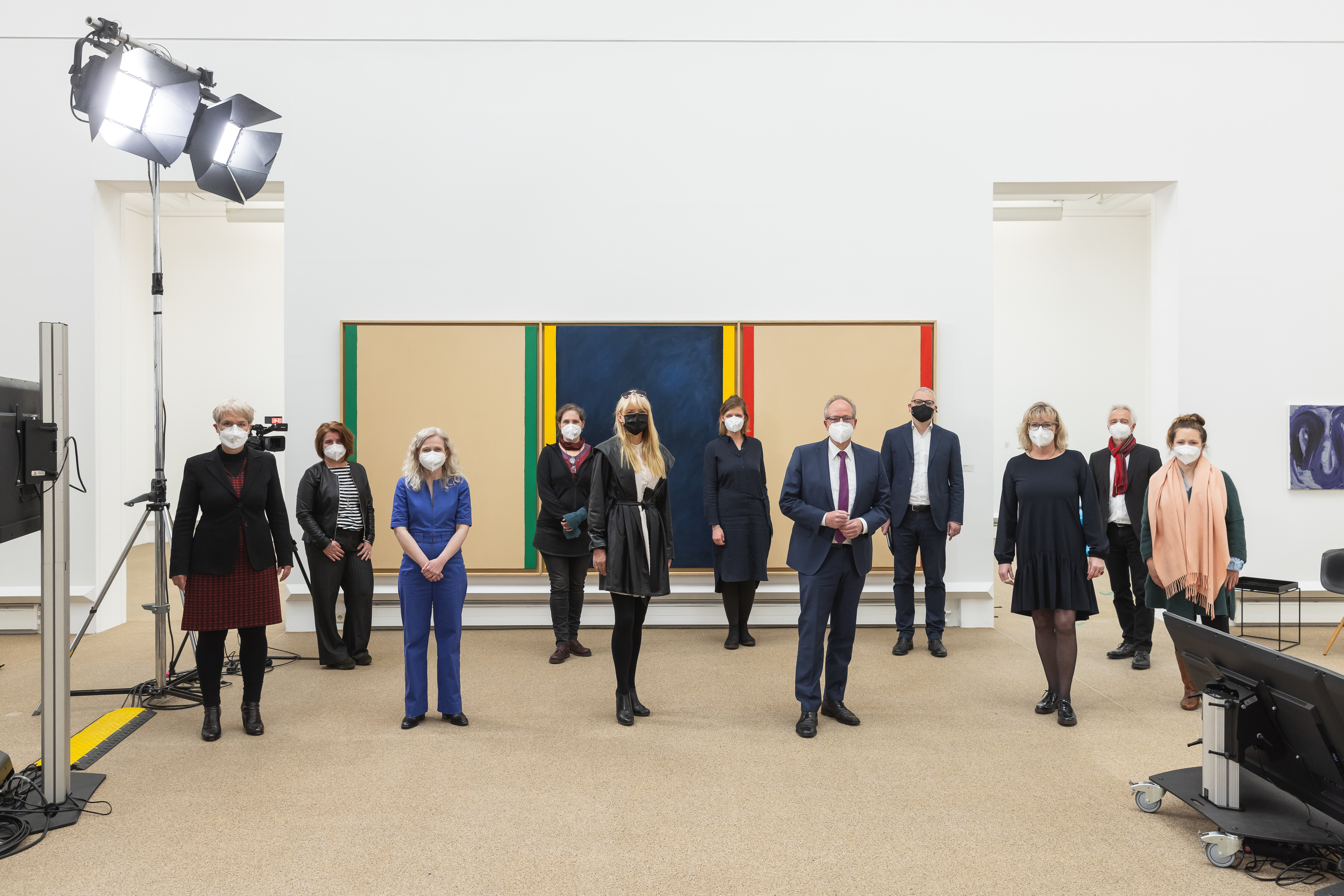 Großer Saal mit Publikum bei einer Konferenz vor einer Bühne mit drei sitzenden Personen und einer großen Leinwand