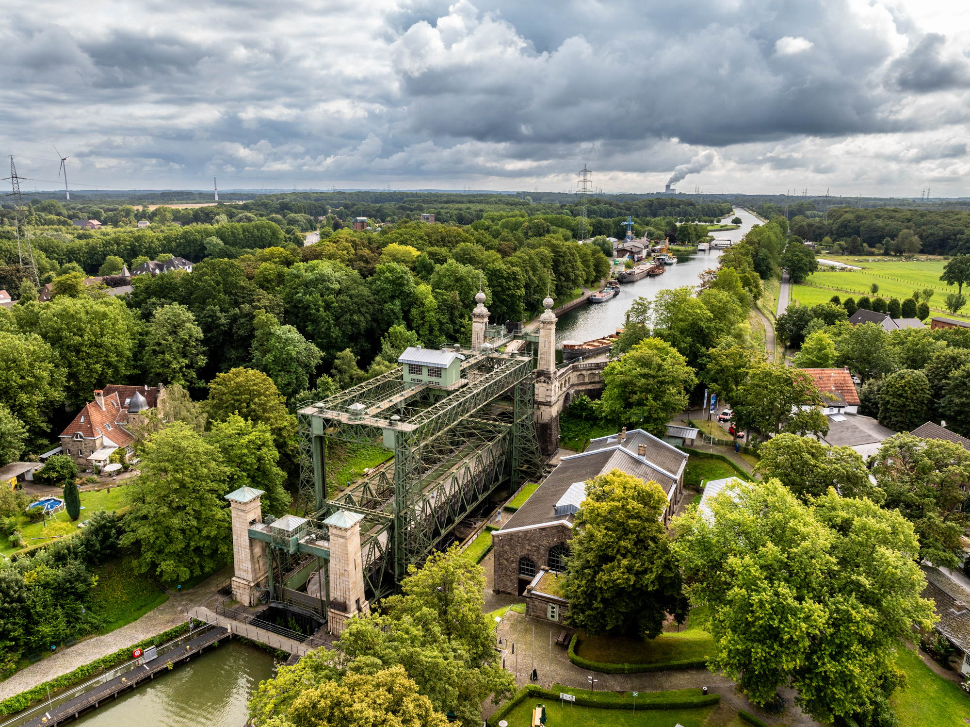 Luftaufnahme eines historischen Schiffshebewerks an einem von Bäumen gesäumten Kanal mit angrenzenden Gebäuden und Feldern