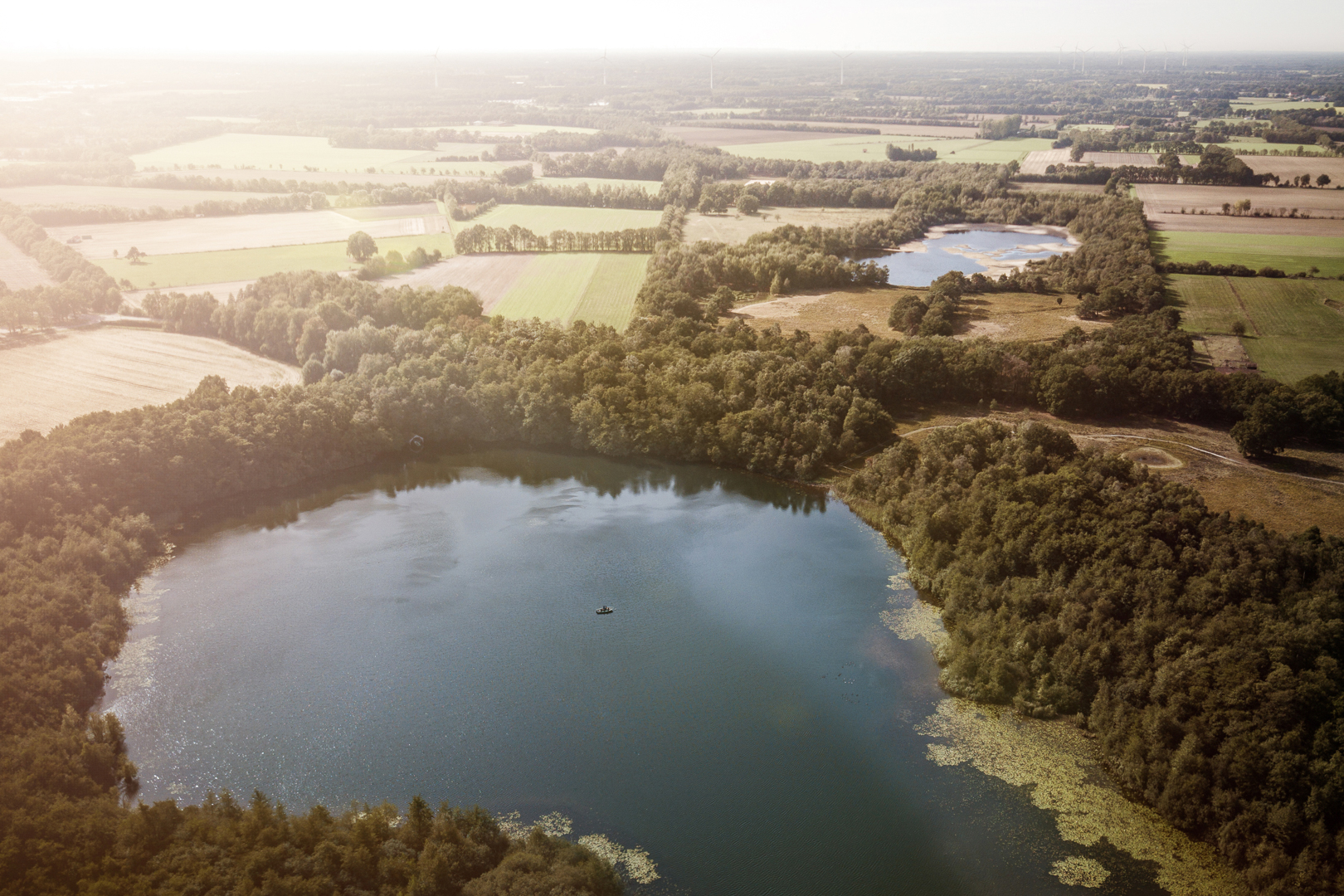 Gelände mit Seen, Wald und Feldern von oben.