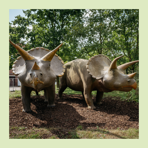 Zwei lebensgroße Dinosaurierfiguren vor dem Eingang des LWL-Museums für Naturkunde mit Planetarium in Münster.