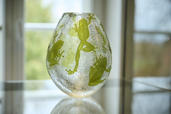 Glasvase mit eingravierten grünen Froschmotiven auf transparentem Grund