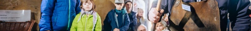 Kinder schauen einem Schmied bei der Arbeit zu.