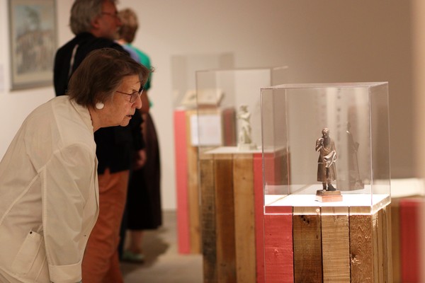 Eine Frau blickt in eine Vitrine, in der eine kleine Figur aus Metall steht.