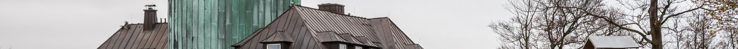 Zwei Menschen stehen vor einer Informationstafel, im Hintergrund das LWL-Besucherzentrum im Astenturm