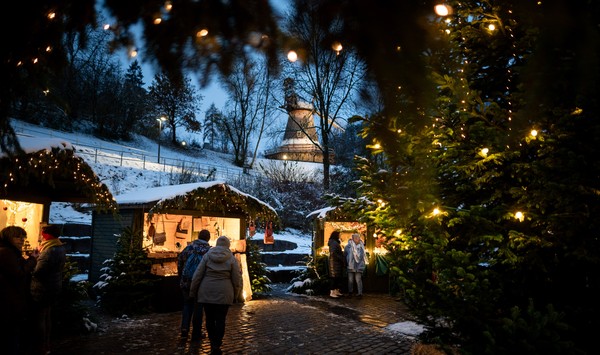 Weihnachtsmarkt am Abend mit Lichterketten und schneebedeckten Dächern