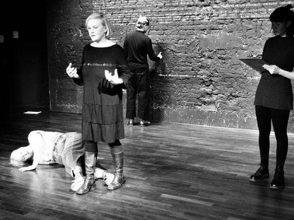 Schwarz-weiß-Aufnahme von vier Schauspieler:innen auf einer Bühne, eine davon liegt auf dem Boden