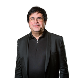 Mann mit Brille und dunklem Sakko vor weißem Hintergrund