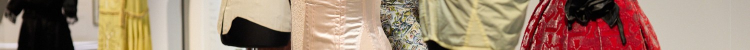 Mehrere Schneiderpuppen mit historischen Damenkleidern und Korsetts in einem Ausstellungsraum