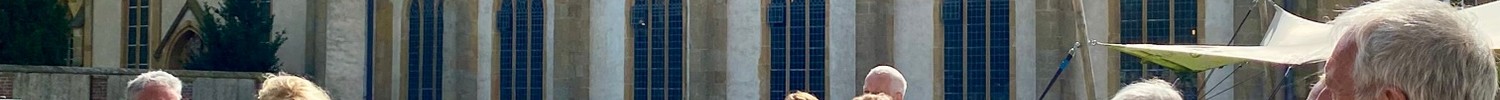 Gruppe von Menschen bei einer Führung vor einem großen historischen Klostergebäude mit spitzbogigen Fenstern und einem kleinen Turm