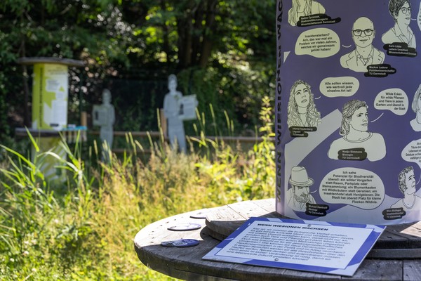 Ausstellungstafel draußen auf einer Wiese.