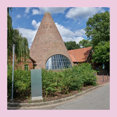 Bild des kegelförmigen Backsteingebäudes der Glashütte Gernheim eingefasst in einen rosa Rahmen