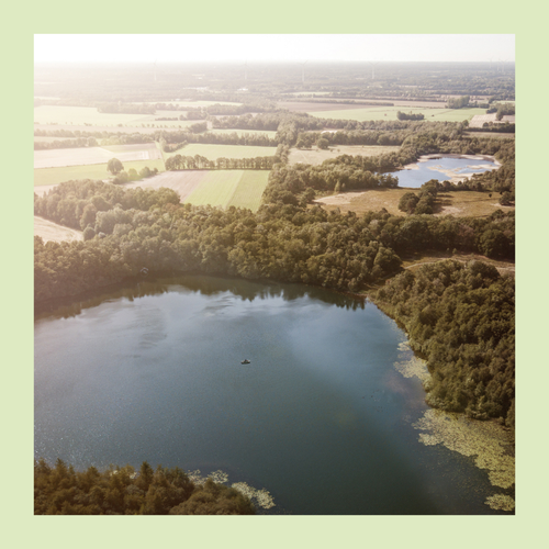 Foto in grünem Rahmen. Auf dem Foto: Das Naturschutzgebiet von oben mit Blick auf eine Seenlandschaft.