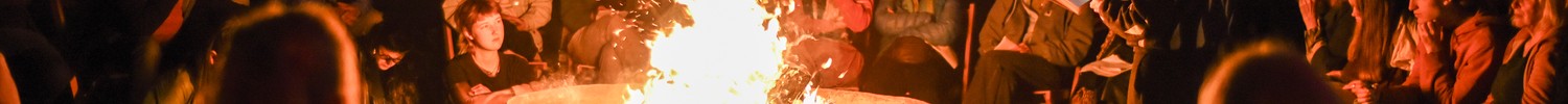 Menschen sitzen bei Dunkelheit um ein Feuer herum