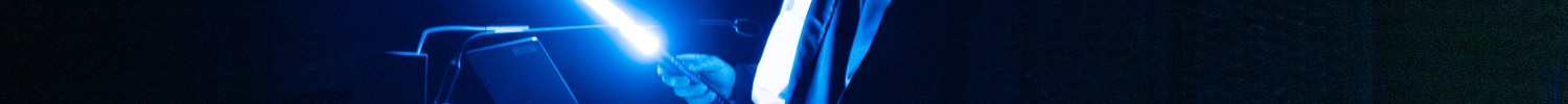 Im dunklen Planetarium steht eine Person zwischen den Sitzreihen. Die Person trägt ein Lichtschwert.