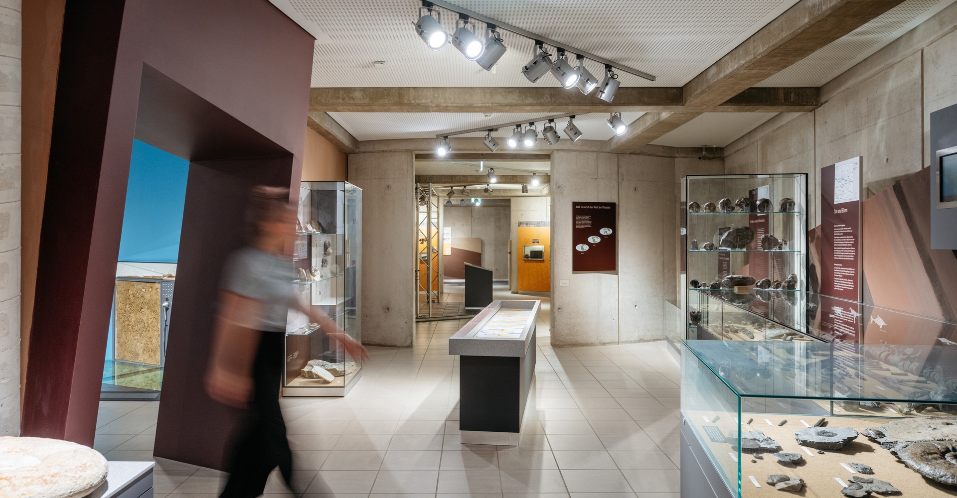 Eine verschwommene Person in Bewegung läuft durch den Ausstellungsraum mit geologischen Funden.