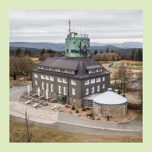 Foto eingefasst in grünen Rahmen. Foto von Gebäude auf der Bergspitze mit Turm und Wetterstation.