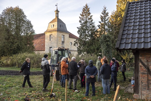 Gruppe von Menschen arbeitet draußen im herbstlichen Park, im Hintergrund das Haus Stapel in Havixbeck