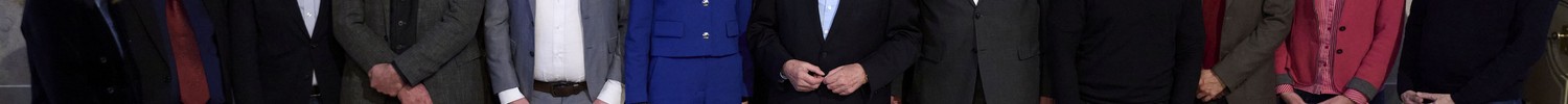 Eine Personengruppe steht in einem historischen Gebäude vor einem Gemälde, davor ein Tisch mit historischem Schriftstück.