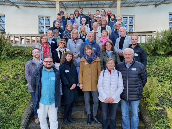 Gruppenfoto von mehreren Personen auf einer Außentreppe vor einem Gebäude mit Fenstern und Geländer