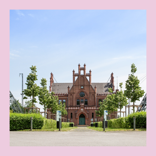 Blick auf Backsteingebäude, links und rechts je ein Förderturm, Bild eingefasst von rosa Rahmen