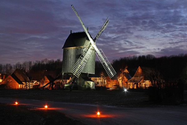 Bockwindmühle bei Nacht im Hintergrund die beleuchteten Häuser des Freilichtmuseums